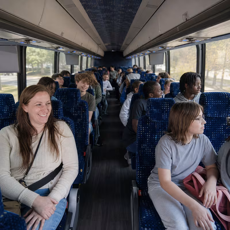 Group boarding a white charter bus for School Transportation transportation in Dallas